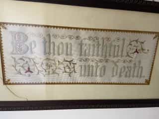 Broderie « Be thou faithful unto death » — accrochée au mur de Geoffrey Clayton